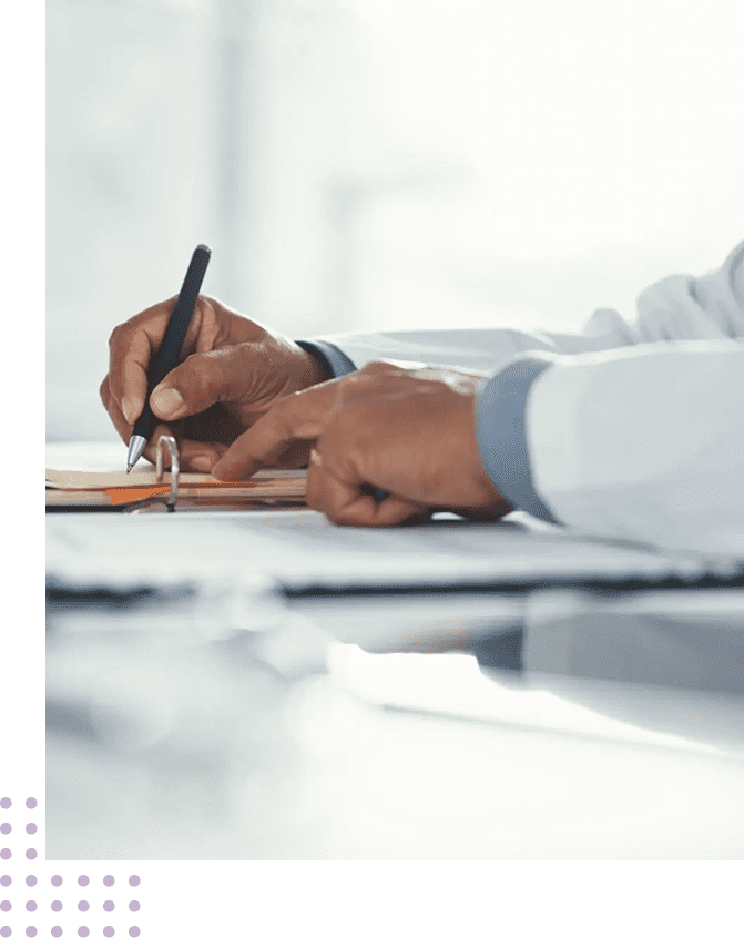 Person signing a contract with a pen on a desk in a professional setting.