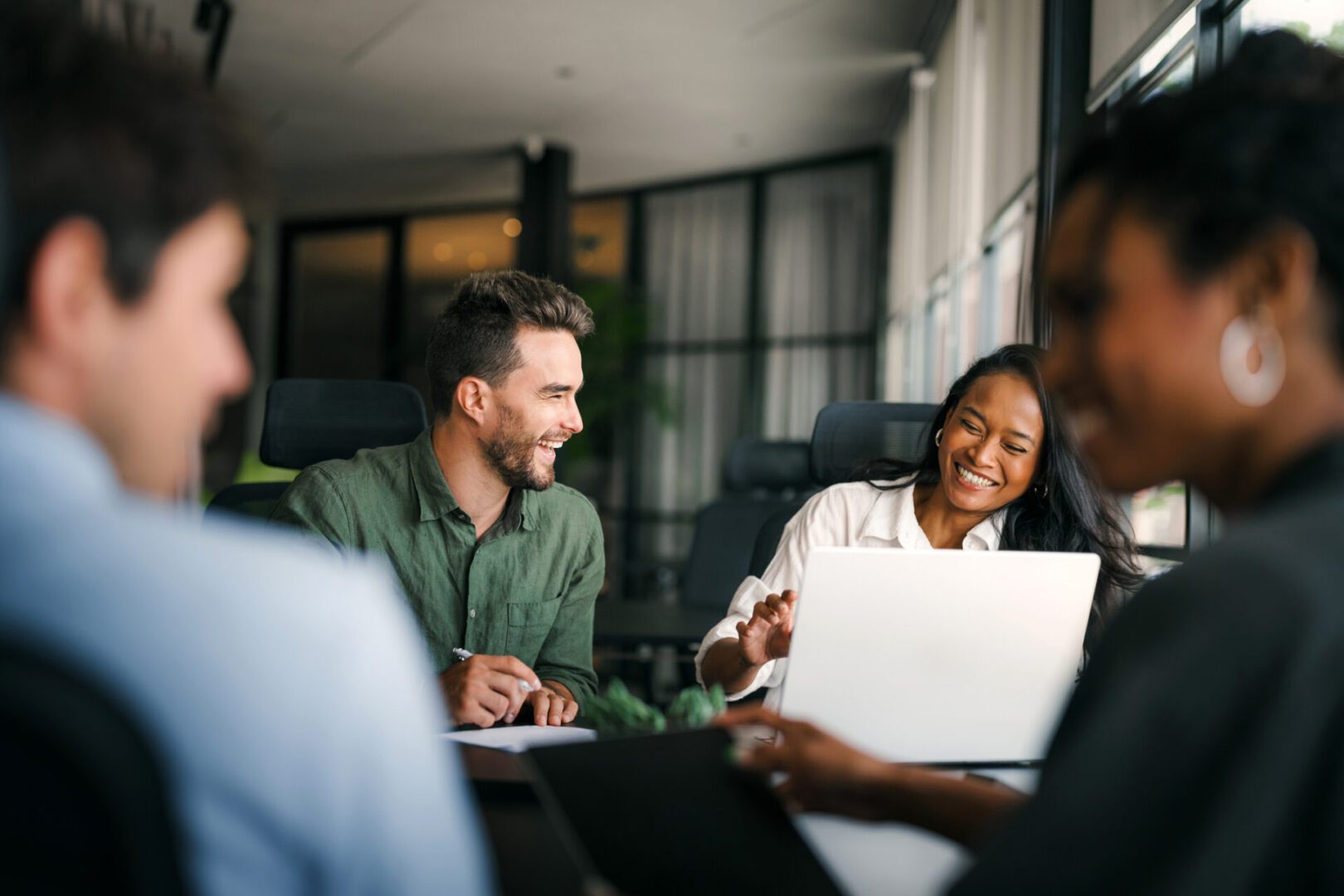 Colleagues collaborate around a laptop in a modern office.