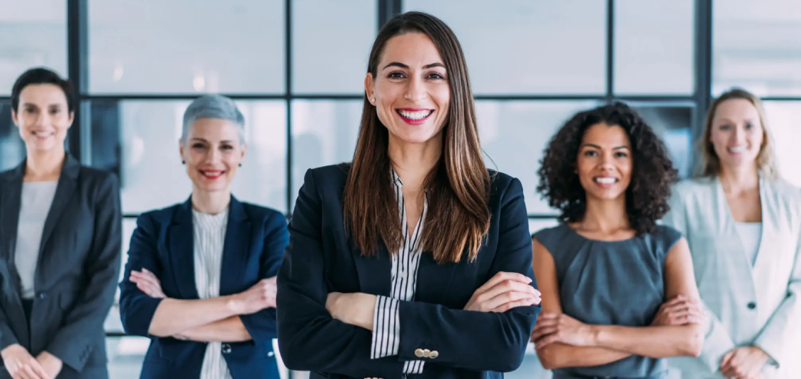 Confident businesswoman smiling with colleagues in the background.