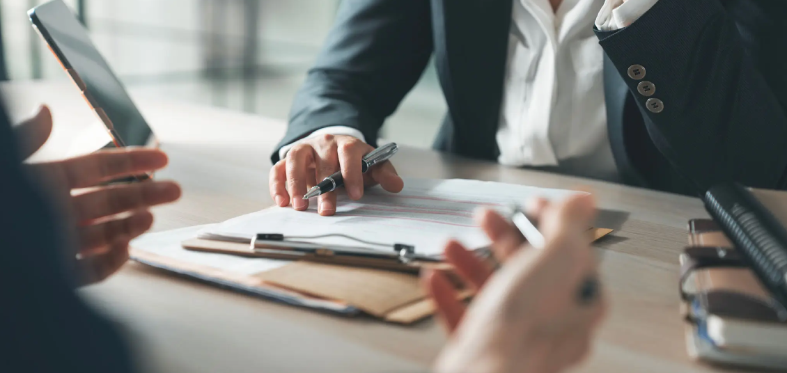 Two people discussing documents with a pen and clipboard.